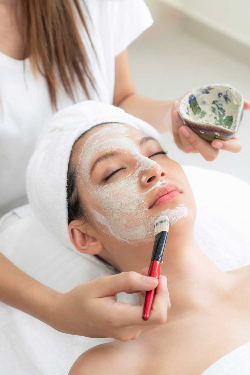 Beautiful woman having a facial cosmetic scrub treatment from professional dermatologist at wellness spa